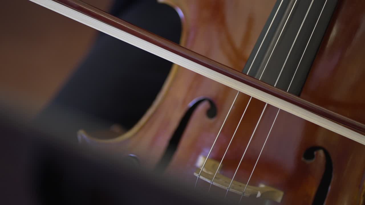 Close up of a cello bow gliding across strings, capturing musical precision - slow motion