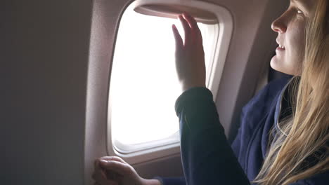 Woman-closing-blind-in-plane-and-using-tablet-PC