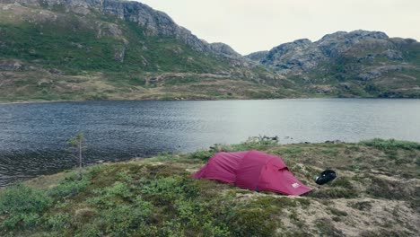 a red camping tent was erected along the shore of pålvatnet lake in åfjord, trøndelag county, norway - orbit drone shot