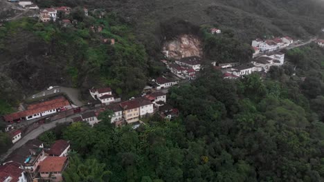approach of mountain road with typical colonial housing to ouro preto, minas gerais, brazil, with part of a hill cut out as part of the mining culture in the area