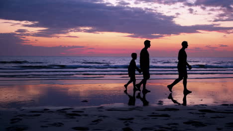 silhouettes of a family walking on the beach at sunset