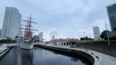 Historisches-Schiff-Angedockt-Im-Stadthafen-Mit-Skyline-Im-Hintergrund-Und-Riesenrad-An-Einem-Bewölkten-Tag