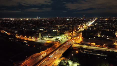 Vista-Aérea-De-La-Ciudad-De-París-Iluminada-Por-La-Noche,-Tráfico-De-Automóviles-En-El-Puente-Sobre-El-Río-En-El-Distrito-Del-Centro-Y-Alrededores-Del-Paisaje-Urbano