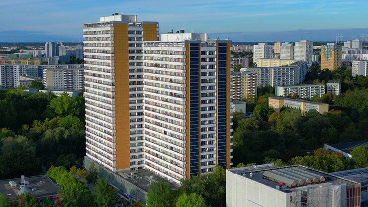 Edifício residencial moderno de arranha-céu com painéis solares integrados na fachada, gerando energia limpa na paisagem urbana de Marzahn. Bela vista aérea panorâmica de drone pairando estático