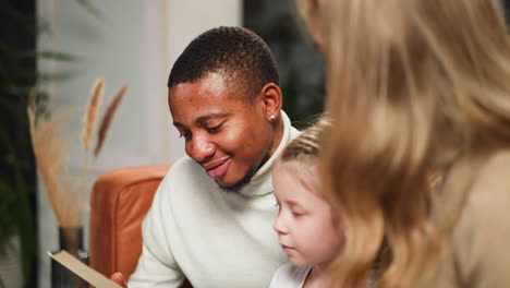 man nods looking at old pictures with woman and little girl