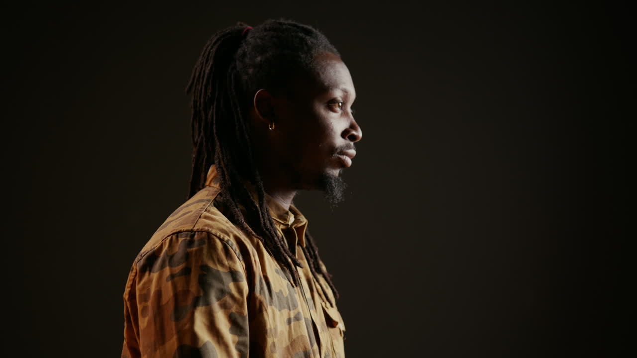 модный крутой парень улыбается перед студийной камерой и позирует