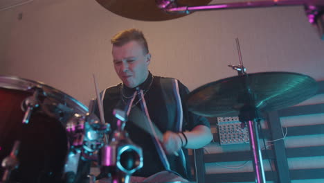 young male musician playing on drums in recording studio