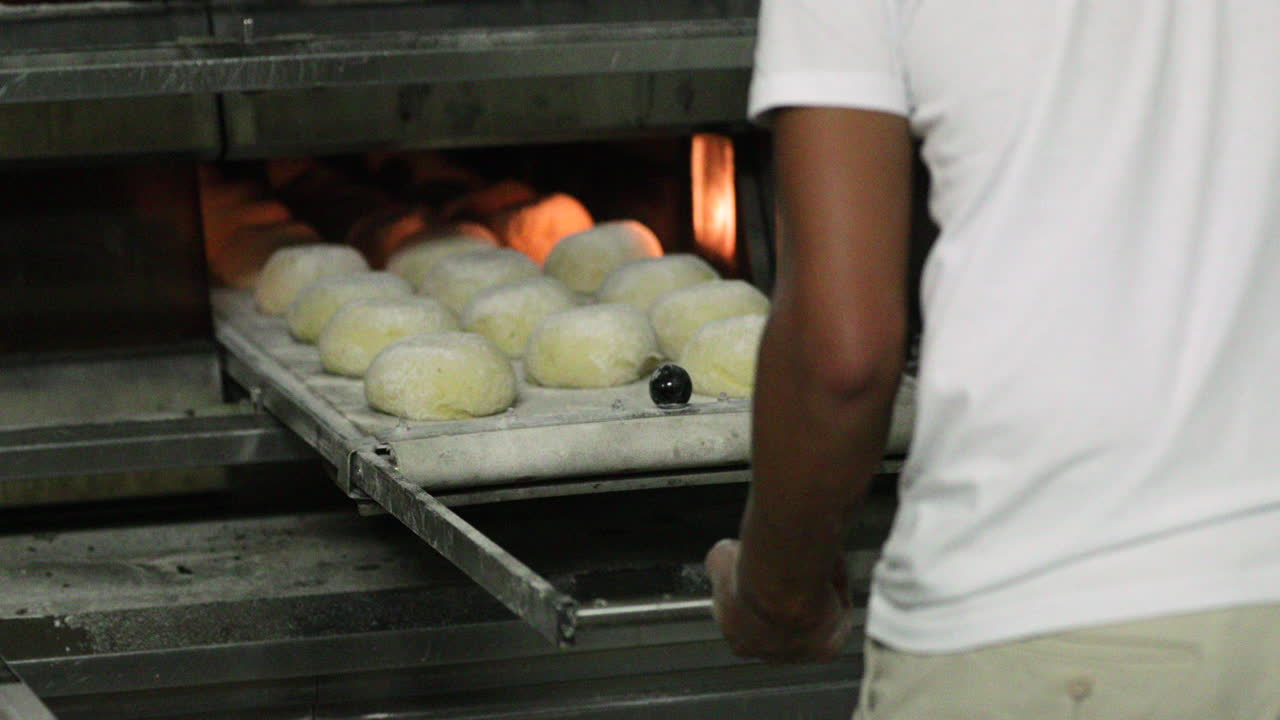 Baker pushing the manual loader with dough inside the deck oven and ...