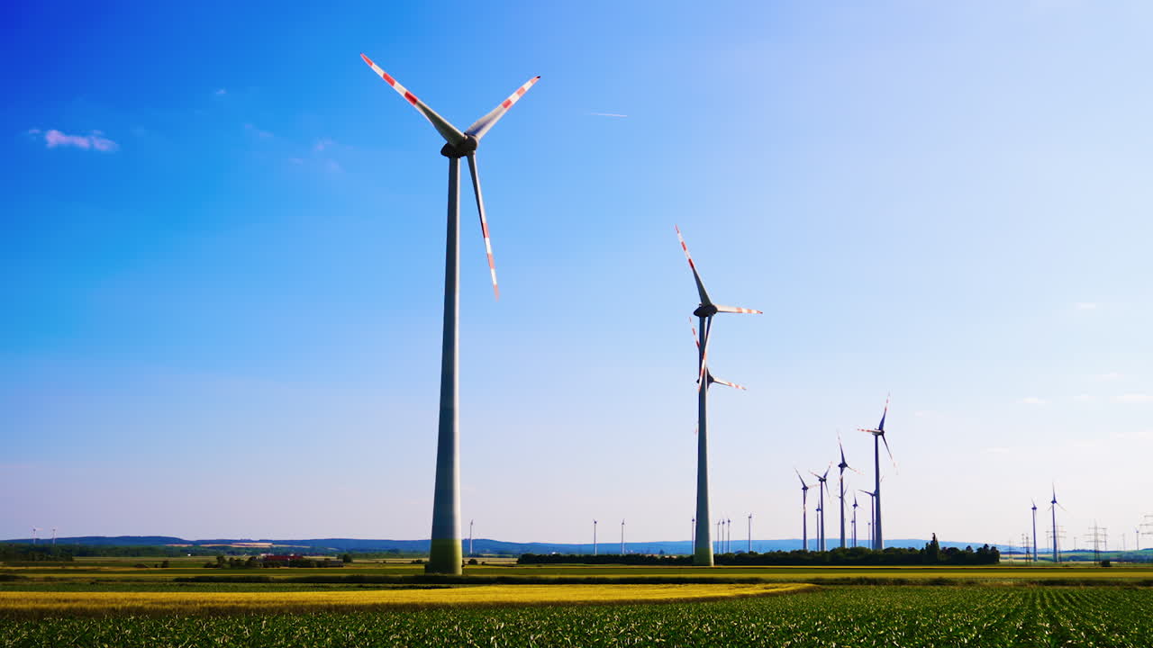 Wind turbines generating clean energy. Large wind turbines stand tall in a rural landscape, harnessing wind energy under a clear blue sky during daytime