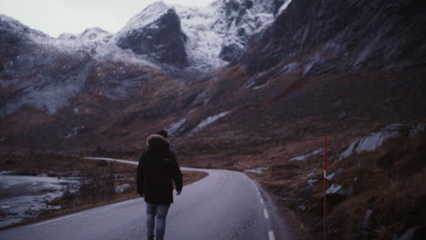 Caminante-Masculino-Irreconocible-Camina-Por-La-Pintoresca-Carretera-De-Montaña-En-Lofoten,-Noruega