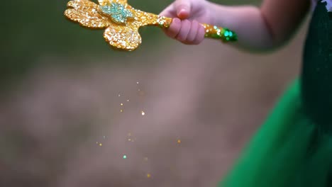 child holding a decorative golden clover-shaped wand