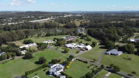 4k aerial view of large rural homes approaching a river with a ferry in australia
