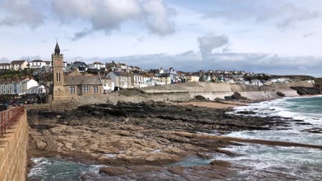 Meereswellen-An-Der-Felsigen-Küste-Von-Porthleven-Mit-Küstenstadt-Und-Glockenturm-Im-Winter-In-Helston,-England,-Vereinigtes-Königreich