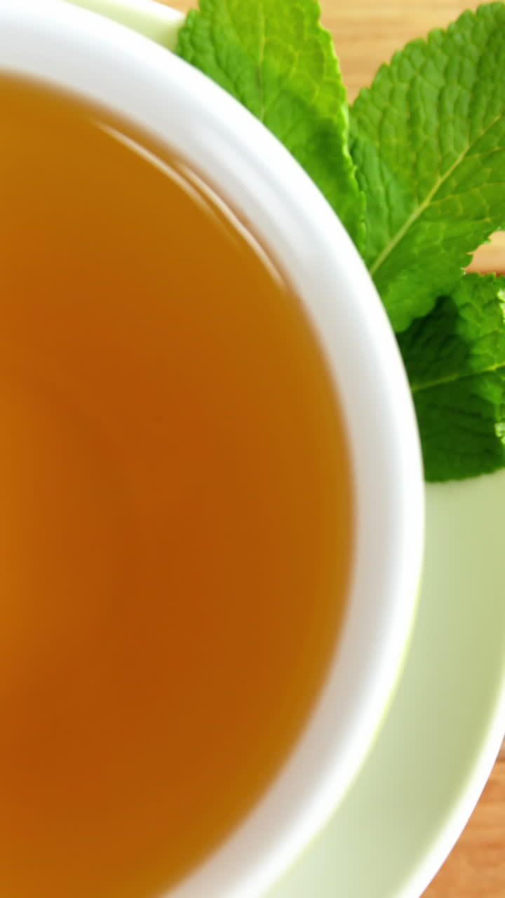 Close-up of tea cup, mint leaves, wooden spoon, dry tea leaves