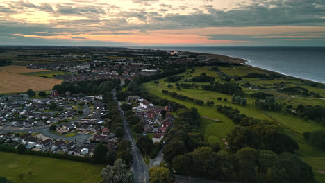 Aerial-drone-video-captures-Skegness-by-the-sea-at-sunset,-revealing-holiday-park,-beach,-sea,-and-caravans-on-sweeping-landscapes