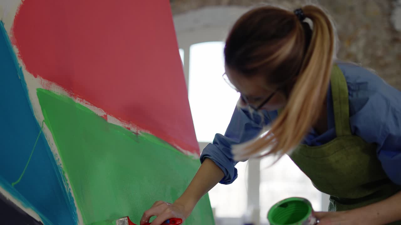 artista femenina trabajando con un gran pincel y color verde con su obra de arte