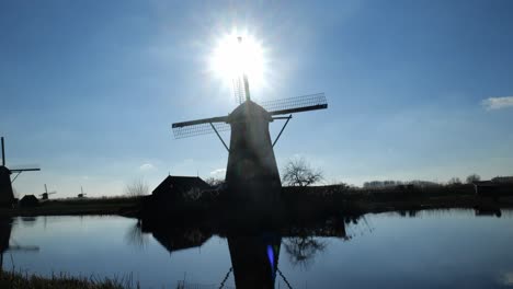 silhouette view of famous windmills in kinderdijk holland beside calm reflective river