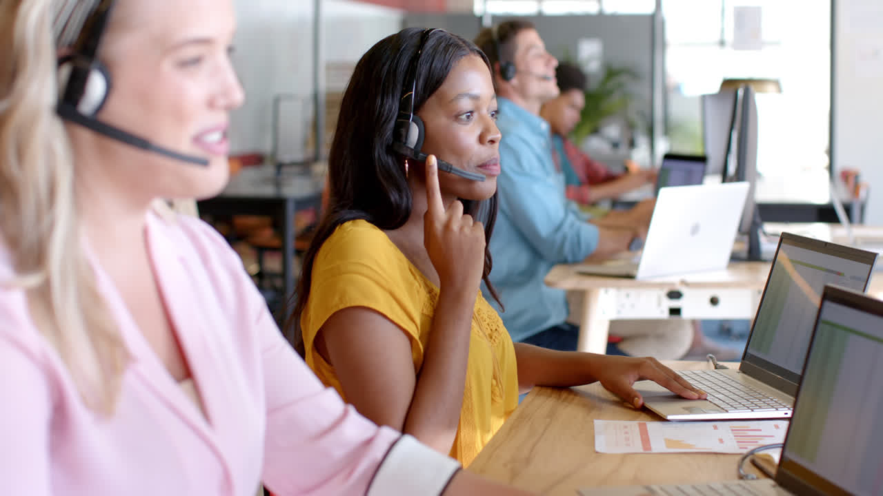 Happy african american casual businesswoman and diverse colleagues using phone headsets, slow motion