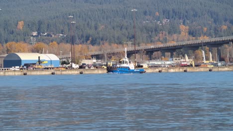 tugboat on the fraser river with vancouver cityscape and autumn trees in the background, sunny day