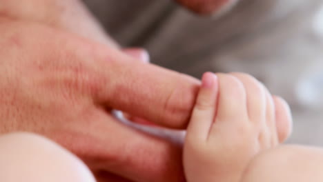 las manos de los adultos sosteniendo las manos de los bebés.