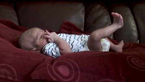 frotando aceite en los pies del bebé recién nacido, acostado en la cama en onesie