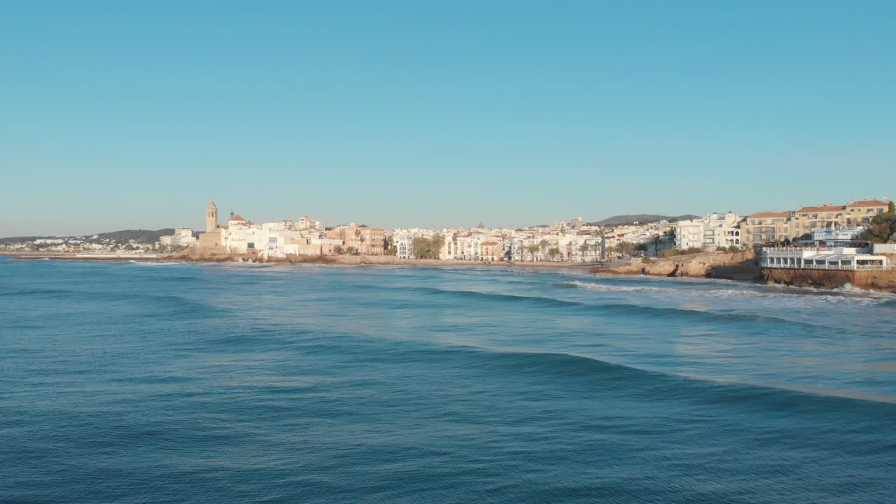 el dron captura la ciudad costera mientras las tranquilas olas del mar se lavan hacia el paisaje rocoso durante la mañana soleada