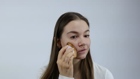 Rutina-De-Maquillaje-De-La-Piel-De-La-Cara-Matutina-Frente-Al-Espejo-Por-Una-Atractiva-Joven-Caucásica-Frente-Al-Fondo-Blanco