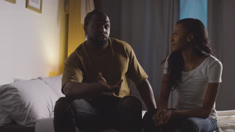 couple at home sitting on bed at night having argument 6