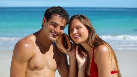 Couple-listening-to-the-water-with-a-shell