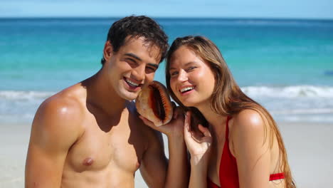 couple listening to the water with a shell