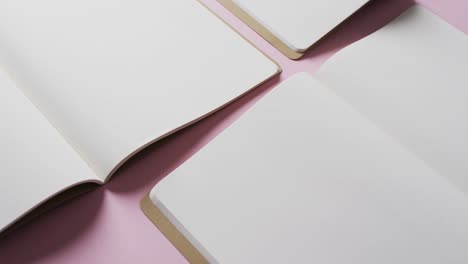 close up of open blank books with copy space on pink background in slow motion