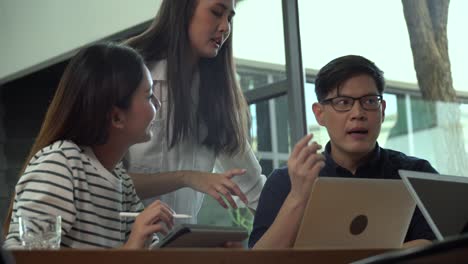 group of young asian business people team meeting at coworking space in modern office discussing business plan and  brainstorm . entrepreneurs man present strategy to partner woman