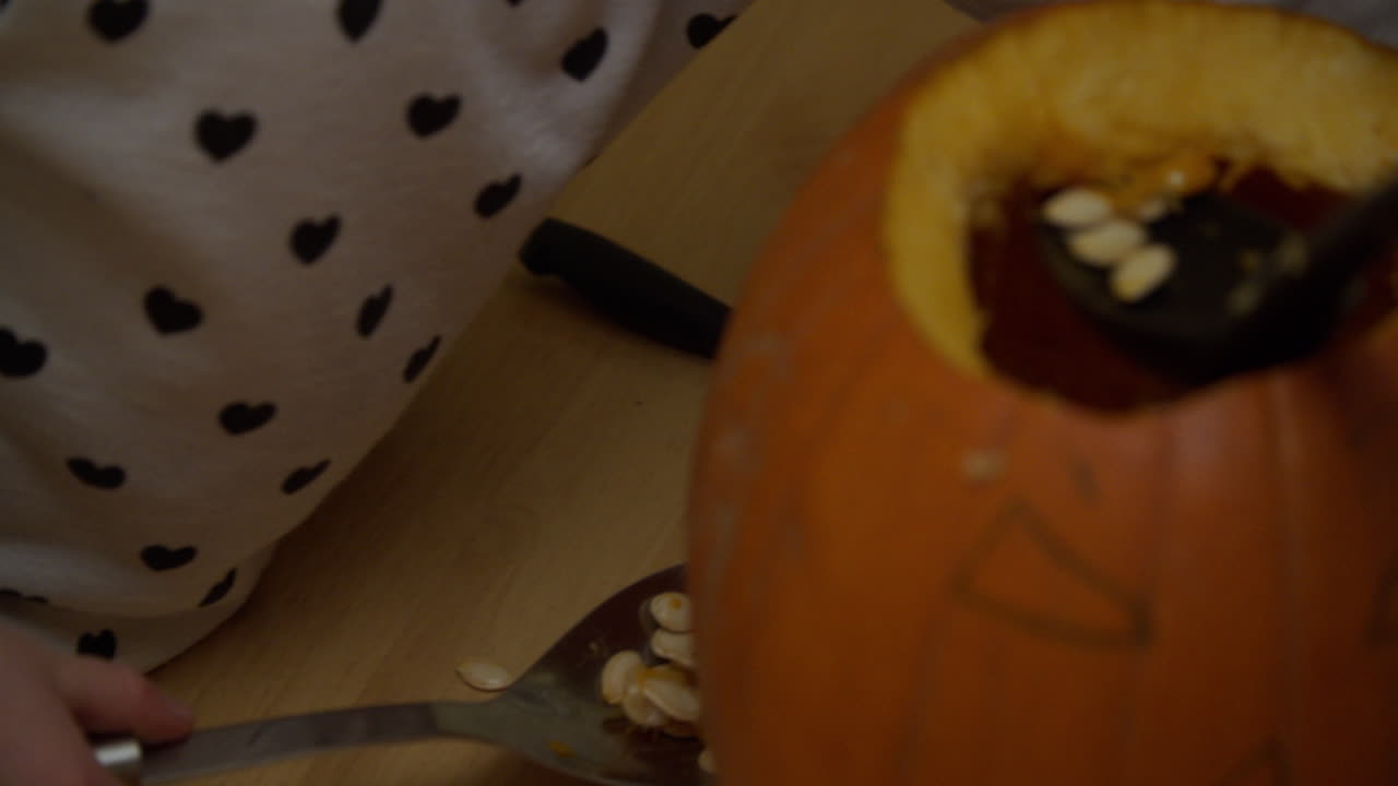 두 명의 어린 아이들이 할로윈을 위해 호박에서 씨 ⁇ 을 제거하고 있습니다.