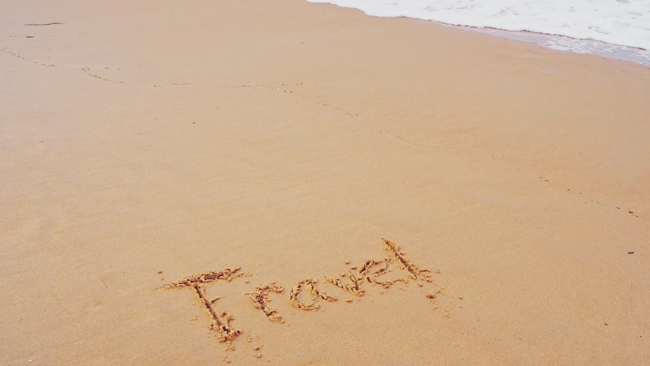 바다 해변에서 문자 여행을 하고 자연 개념의 슬로우 모션 파도로 모래 위에 파도를 튀깁니다.