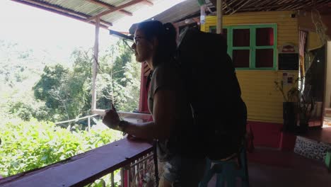 Female-Hispanic-traveler-with-backpack-walks-to-hostel-balcony-rail