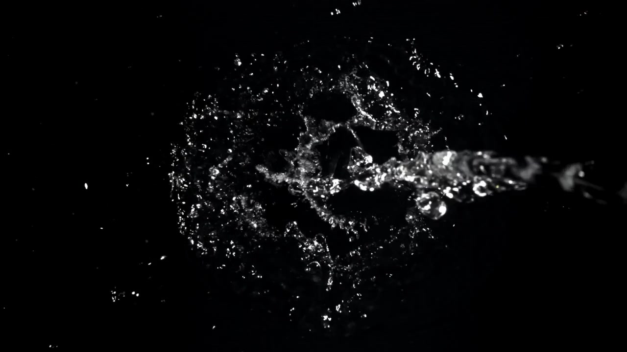 Vandstrøm der sprøjter på sort baggrund i slowmotion