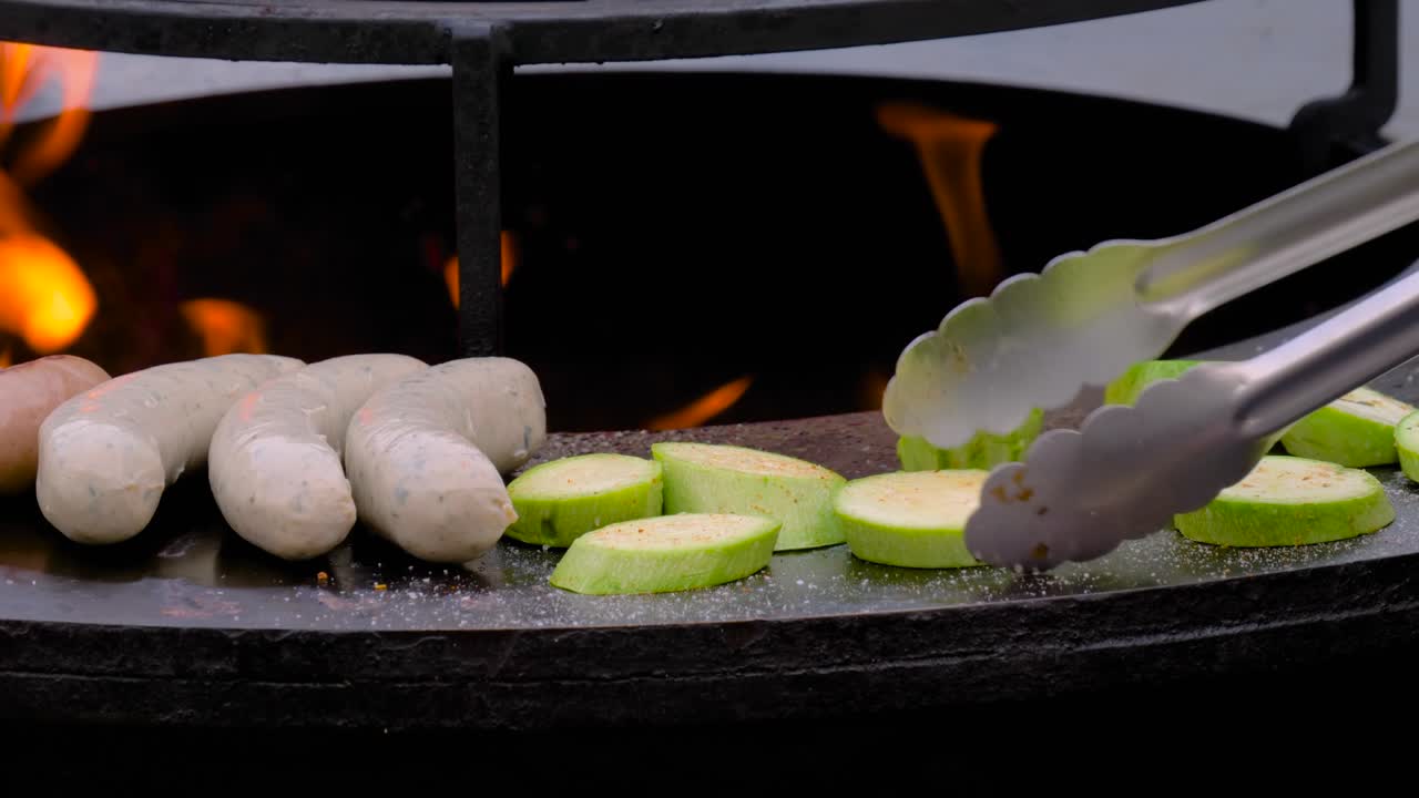 느린 동작: 셰프가 뜨거운 불꽃으로 브레이저에 소시지와 zucchini를 그릴