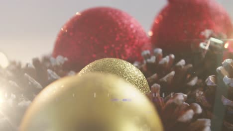 animation of christmas gold, red baubles and pine cones decorations