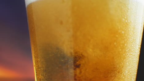 la cerveza fría macro en cámara lenta se vierte en un vaso con transpiración. las burbujas de cerveza suben a la superficie.