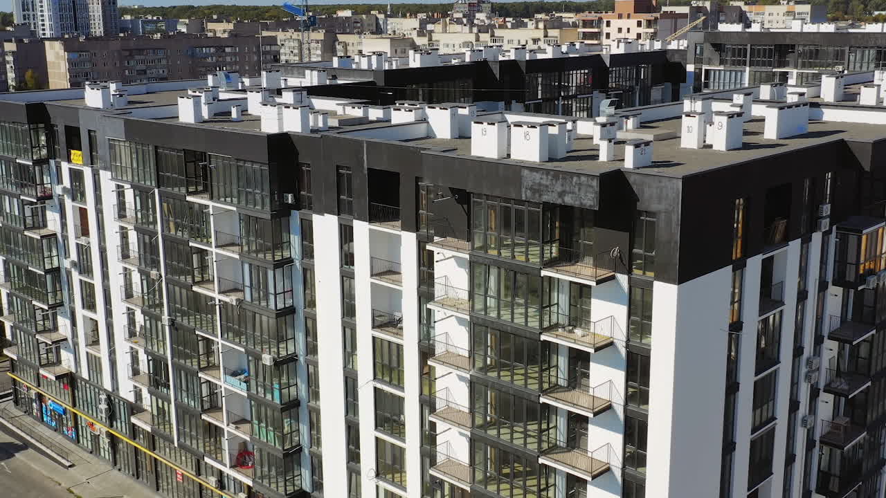 New architecture in the city. High-raise apartment buildings near the road. Modern design of multistorey building. Drone flight.