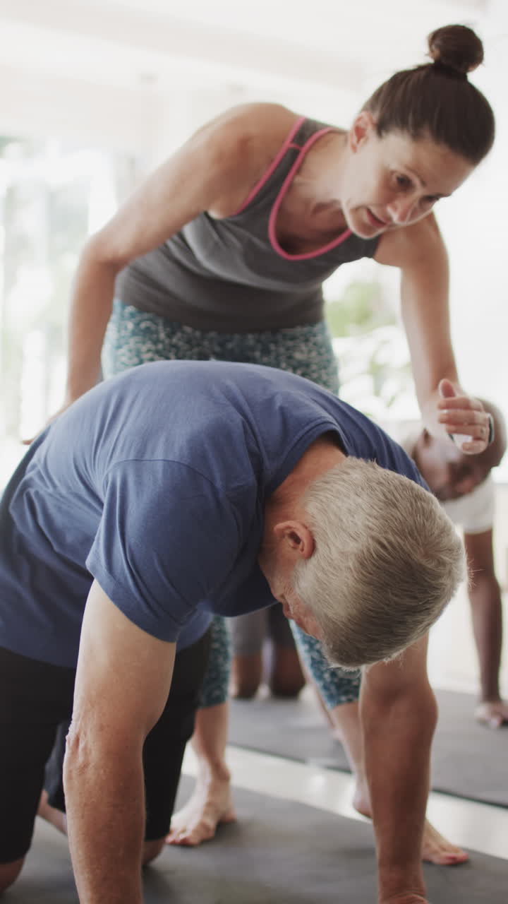 Vertical video of senior diverse people exercising with female coach in slow motion