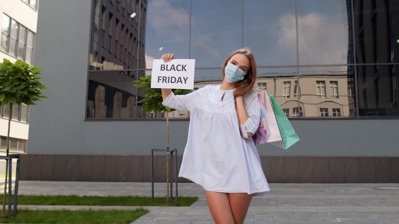 niña con máscara protectora con bolsas de compras que muestran la inscripción de viernes negro durante el coronavirus