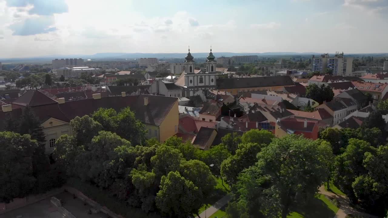 dron giratorio y ascendente disparó sobre una ciudad con iglesias y árboles verdes y exuberantes