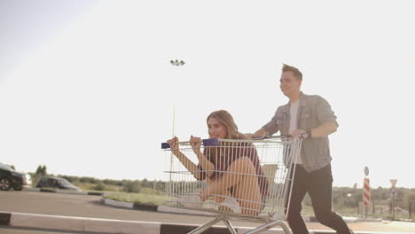 young friends having fun on shopping trolleys. multiethnic young people racing on shopping cart. slow motion