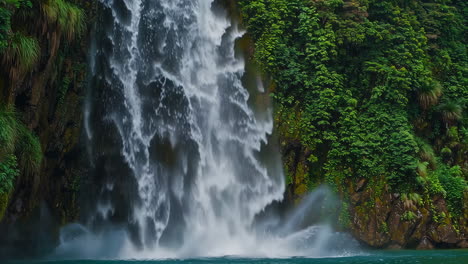 a powerful waterfall cascades into a tranquil pool surrounded by lush green cliffs
