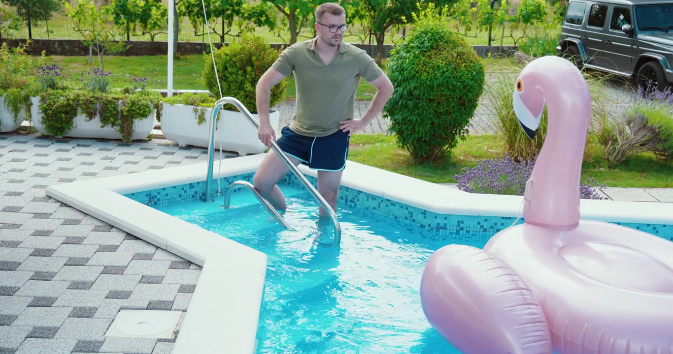Homem prendendo uma boia inflável de flamingo para evitar que ela se afaste.