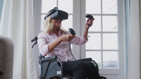 mature disabled woman in wheelchair at home using virtual reality headset gaming holding controllers