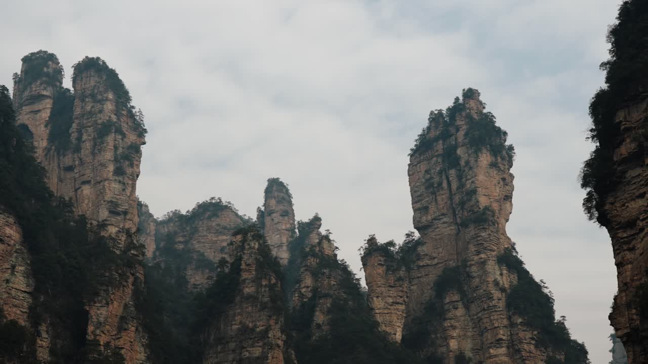 Dramatic vertical rock formations rise into the clouds in Zhangjiajie National Forest Park, China.