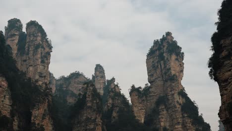 dramatic vertical rock formations rise into the clouds in zhangjiajie national forest park, china.