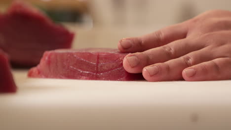 chef cutting a fresh tuna fillet on a chopping board using a sharp knife